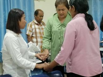 Three Cambodian women and a man holding hands in prayer.
